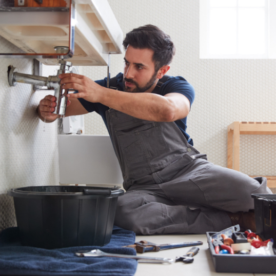 Man fixing pipe beneath sink