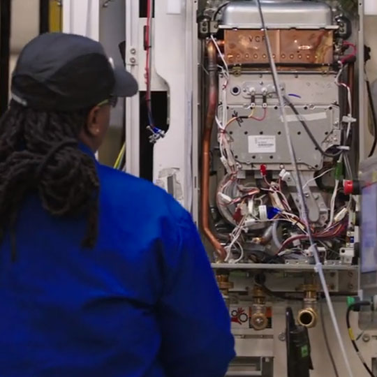 Worker looking at the inside of a water heater